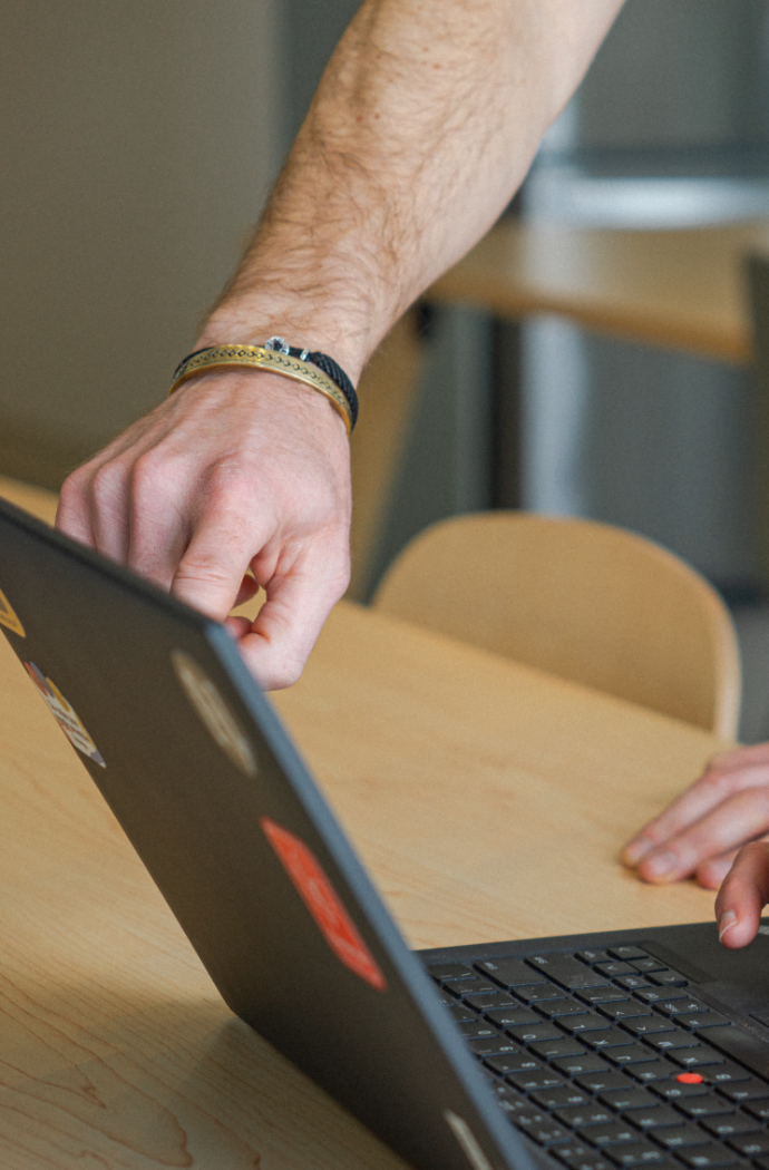 Mains pointant l'écran d'un ordinateur portable d'un employé de Numigi